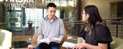 Two students sitting in library with open books