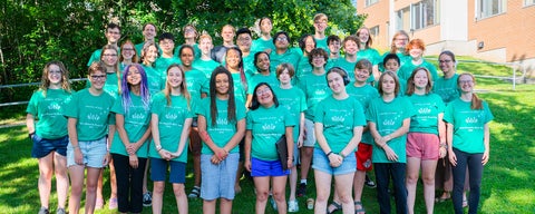 A group of young adults wearing bright green tshirts pose for a group photo outside Grebel