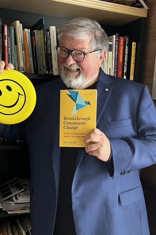 Paul holding a smiley face and a book