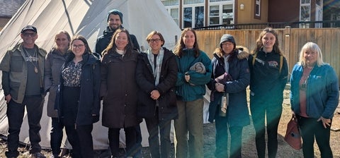 group standing in a line in front of a Tent