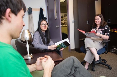 Two students sit in an office, speaking with Gemma, the student life and recruitment coordinator for Grebel.