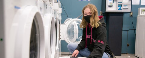 Grebel student wearing a Math department sweater loading laundry machine