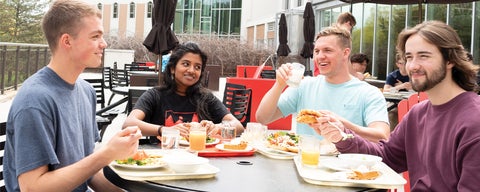 Four Grebel students enjoy lunch outside on the patio. 