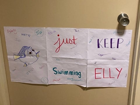 A sign on a door that says "just keep swimming Elly" and other people have signed their name
