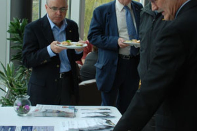 Henry Paetkau points out details of the building to Ken Coates, while David Perrin and Glenn Cartwright look on