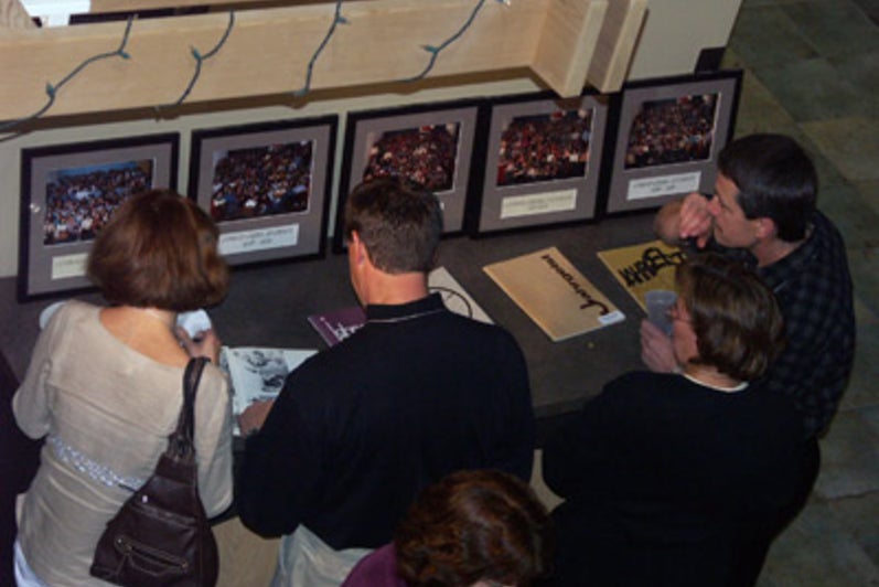 Group of four people looking at five framed photos that are sitting on a table.