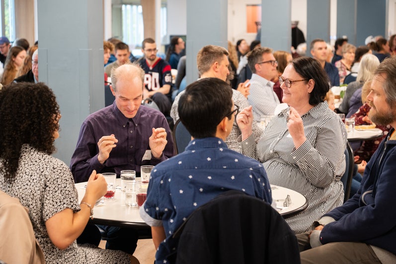 A group of adults sit together at a table in the Grebel dining room