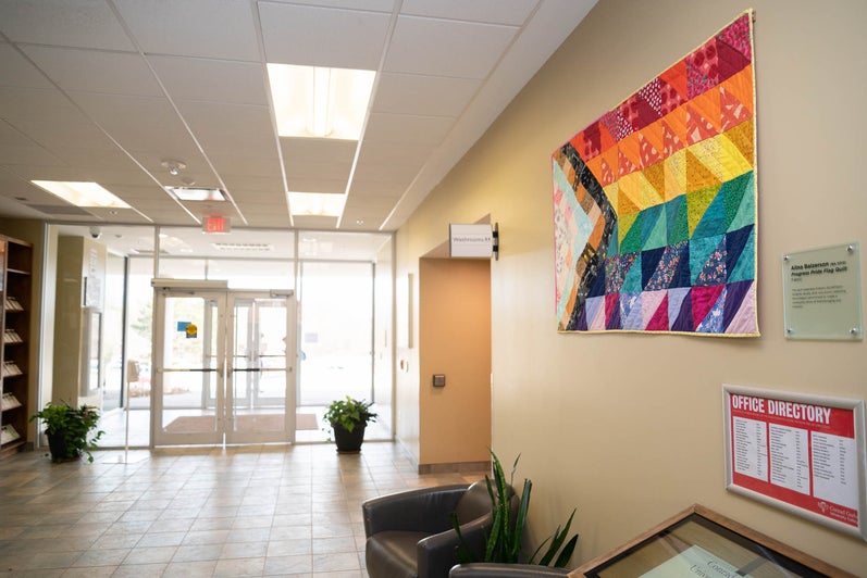 The colourful progress pride hangs on a wall in the front foyer, at the entrance to the Grebel building. 