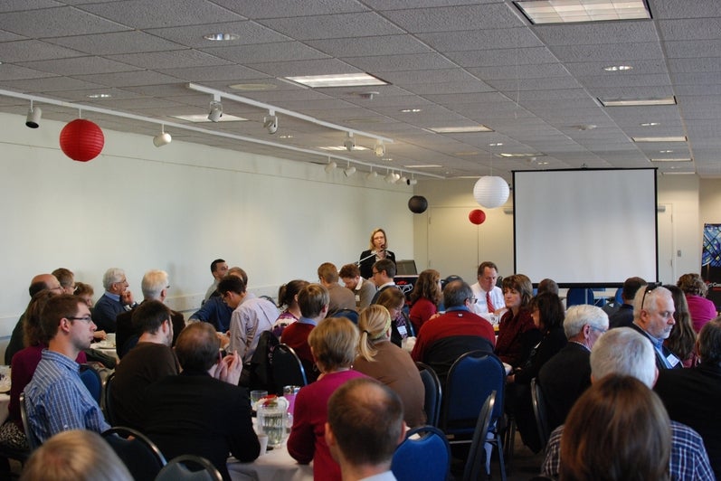 people at tables listening to speaker