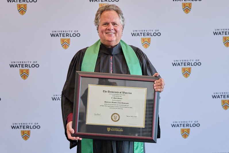 Paul Penner posing with honorary degree from the University of Waterloo