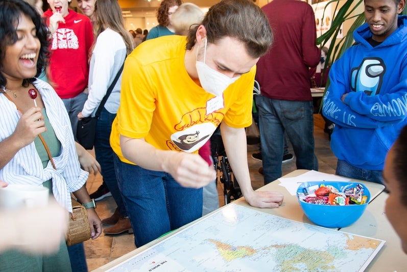 Grebel students in bright single colored shirts looking at a world map 