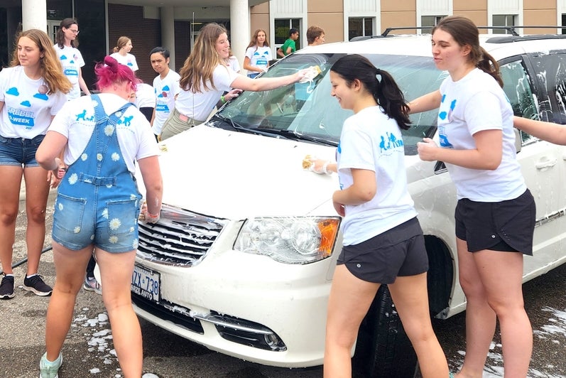 Grebel students washing a white mini van outside 