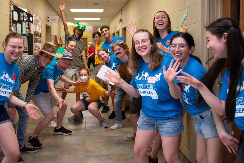 students in blue Grebel shirts welcoming students to the dorm hallway 