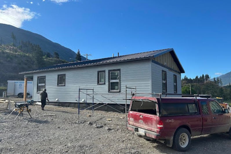 A long house and a red truck with mountains in the background