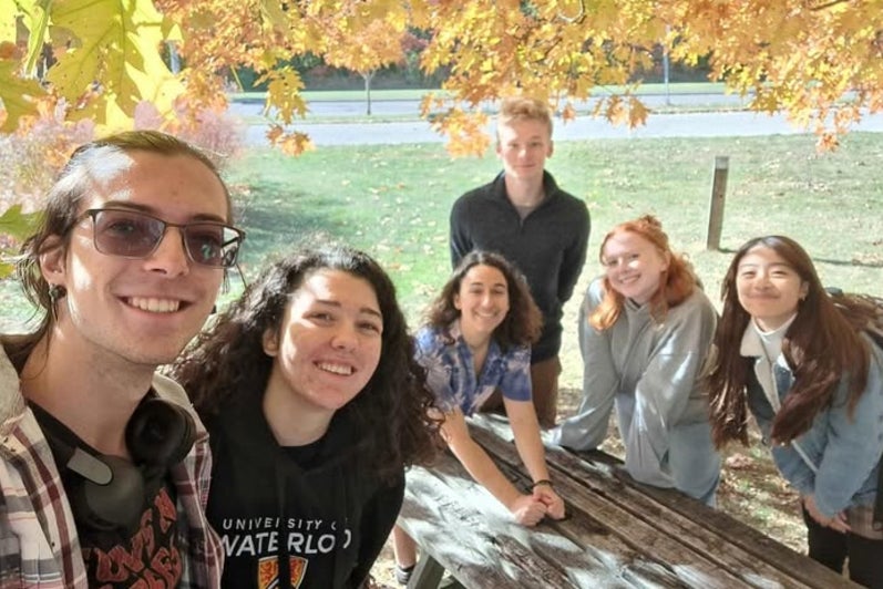 A group selfie with students at a picnic table in the fall