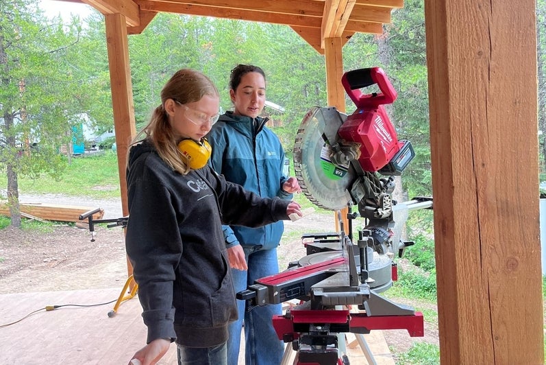 Mona and another volunteer using a power saw on site