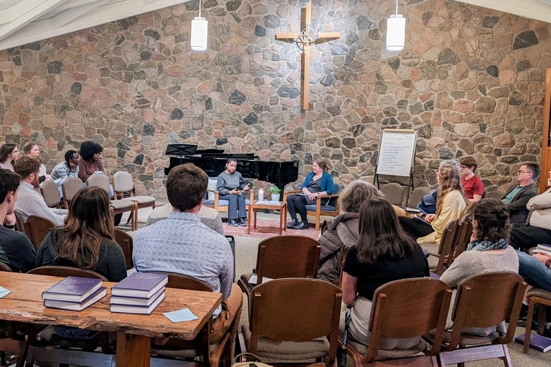 crowd in chapel listening to two people at the front of chapel 