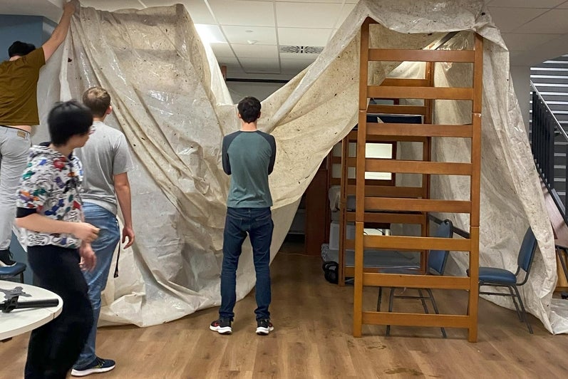 students hanging a tarp in the cafeteria 