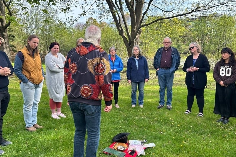 grad students stand outside, listening to Terry speak
