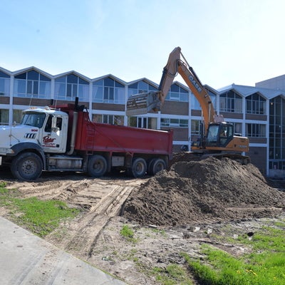 A backhoe begins digging on a bright sunny day