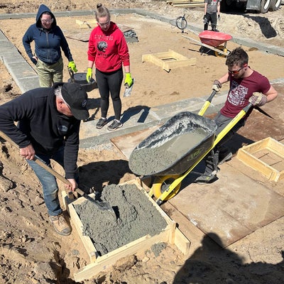 3 students pouring a concrete foundation