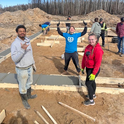 three students celebrating their new cement smoothing skills