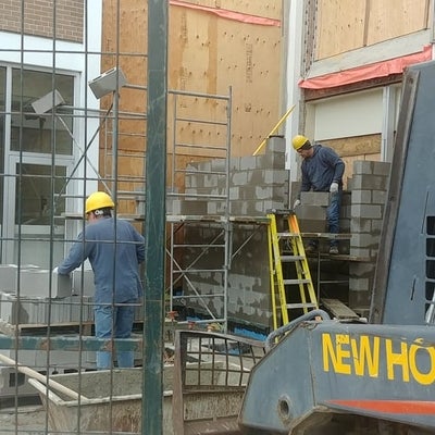 workers lay cinder blocks for the elevator shaft. 