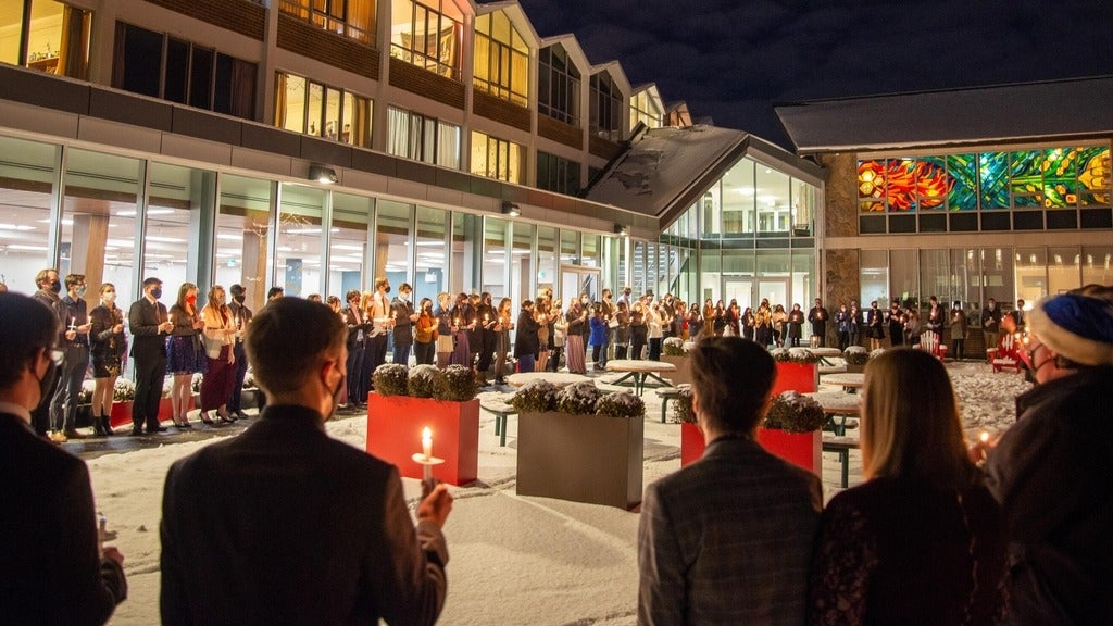 Students holding candles outside in the snow