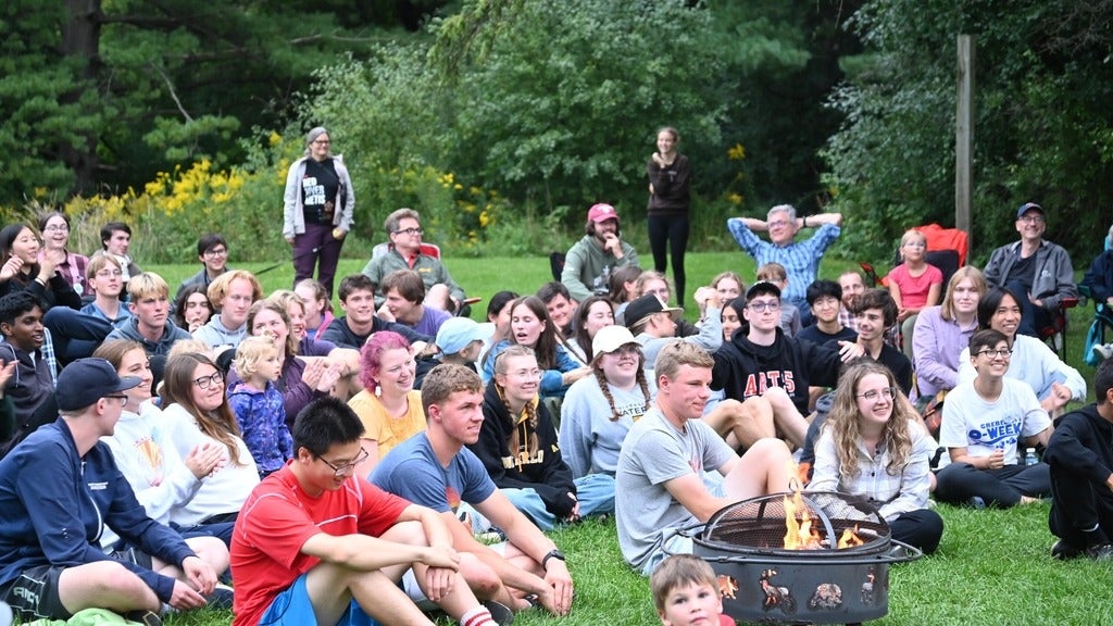grebelites gathered around a campfire with staff and faculty