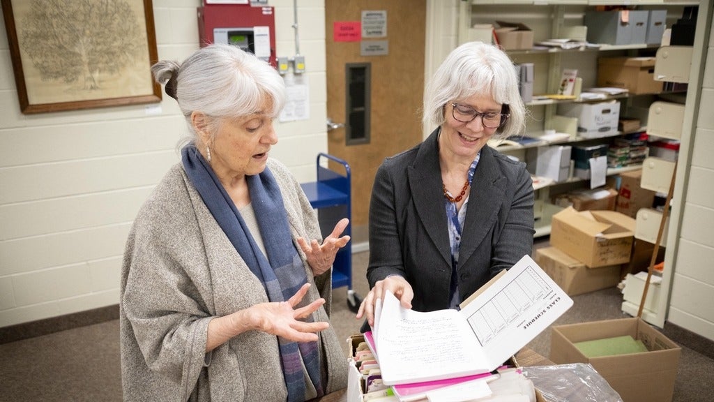 Hildi Froese Tiessen and Laureen Harder Gissing look through a box of materials in the archives