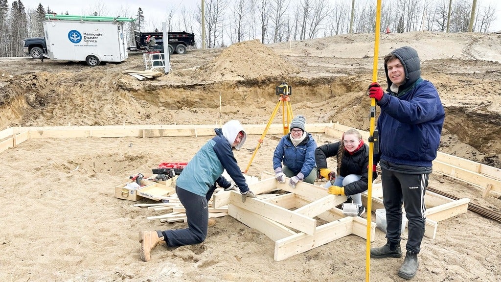 four students building wooden frames for pouring concrete