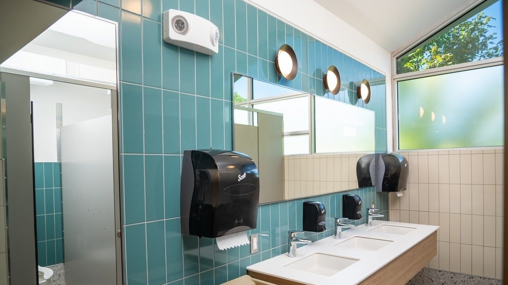 A well lit grebel washroom with light blue tile