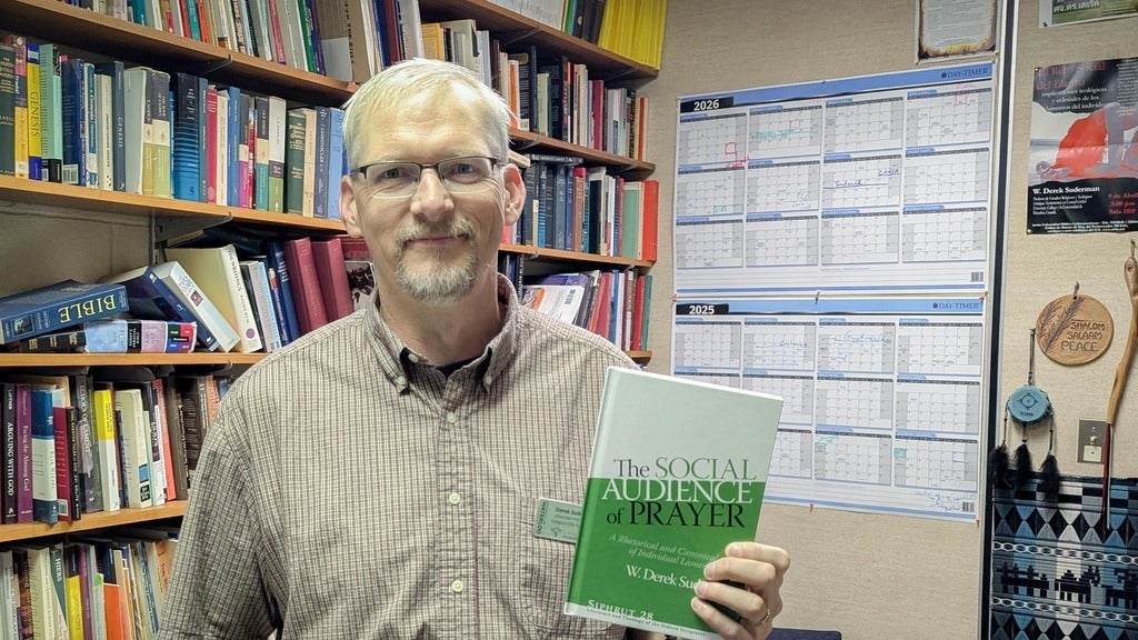 Derek Suderman holding his new book