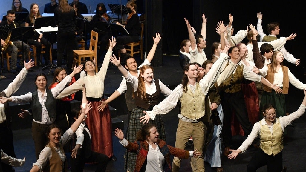 cast of something rotten posing with their arms up 