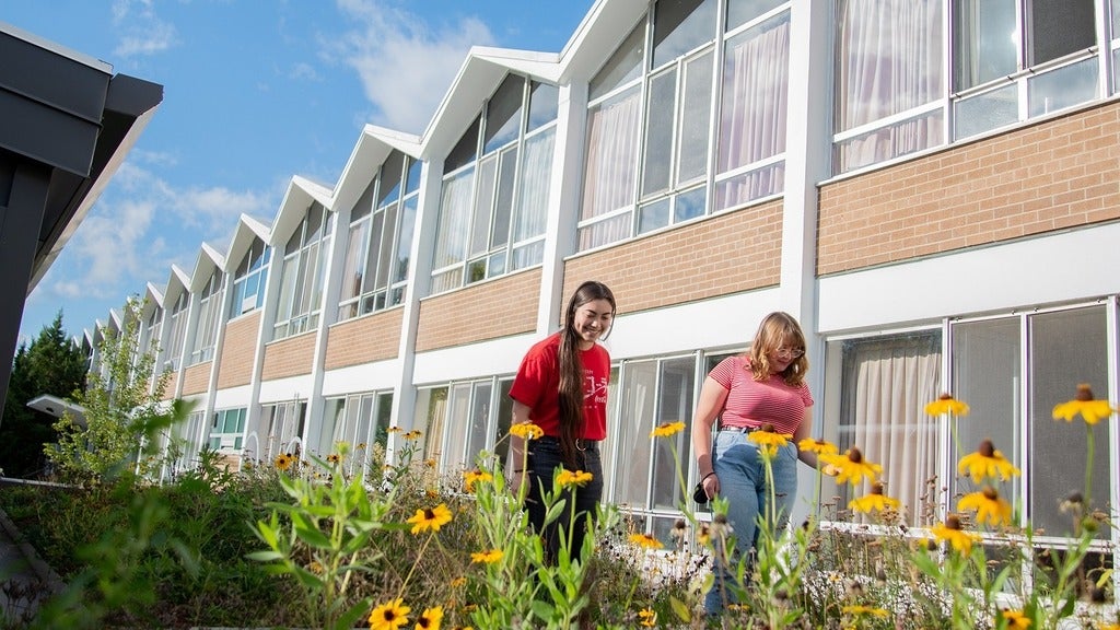 two students walking through garden in front of Grebel Residence 