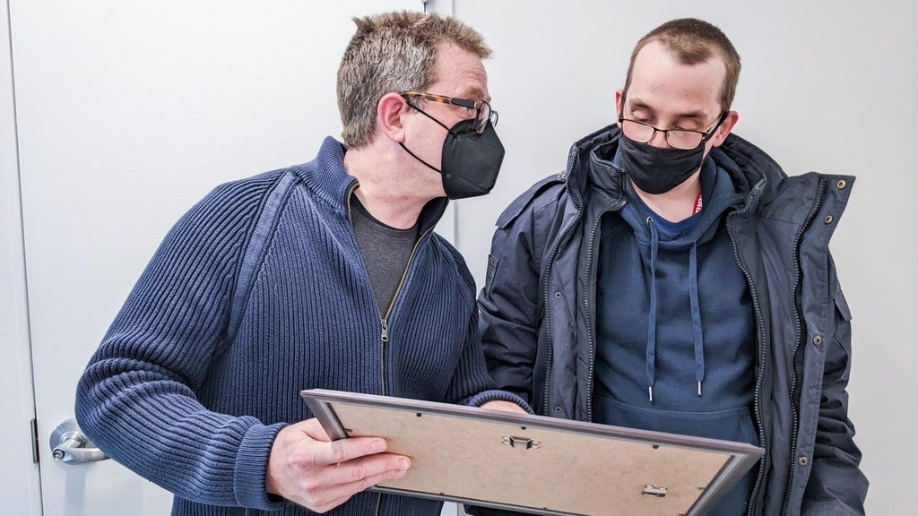 Tyler looking at a certificate in a frame Marcus is holding