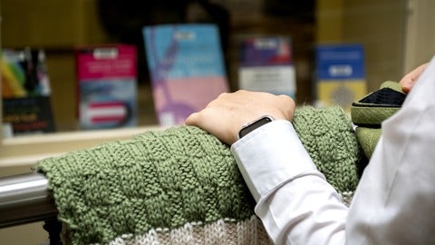 Hand on a prayer shawl with 2SLGBTQ+ books in the background