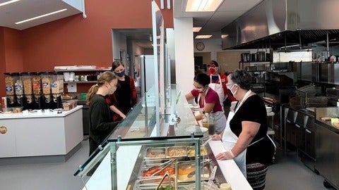 side view of a buffet kitchen line with everyone wearing masks 