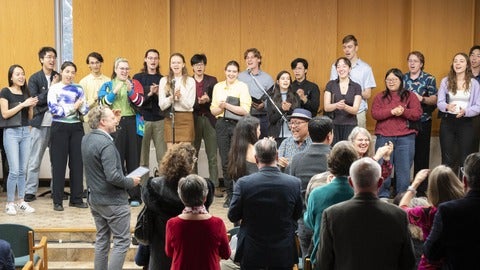 group of people surounding a mic singing