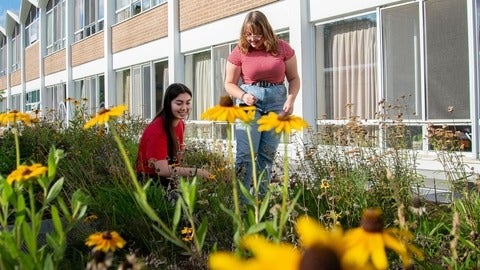 two students standing in pollinator Garden
