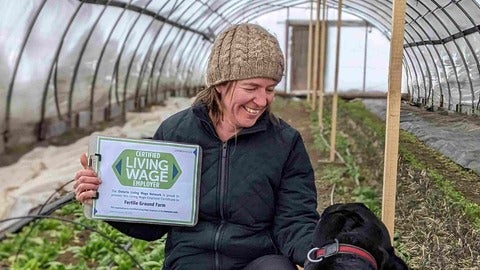 Angie holding a sign saying "certified living wage employer" 
