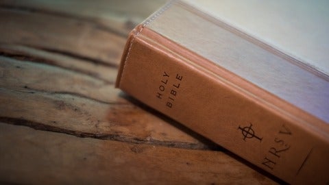 brown holy bible sitting on wood
