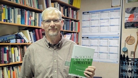Derek Suderman holding his new book