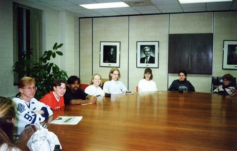 group of students gathered aorund conference table 