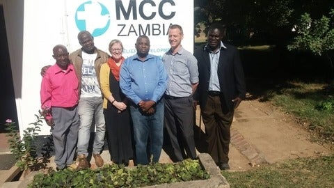 issa daniel posing with people in fornt of MCC office in zambia 