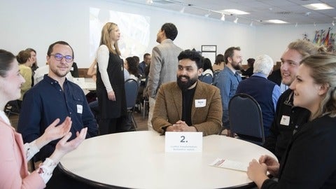 people sitting around a round table talking to eachother 