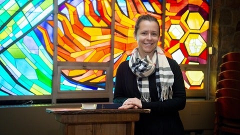 Kathryn standing beside a podium in fornt of stained glass window