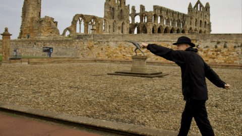 Len Friesen copying a pose of a statue behind him