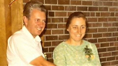 two people posing by a brick wall 