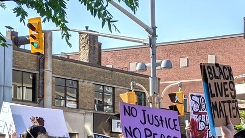 a bunch of protest signs being held above heads while walking down a street 